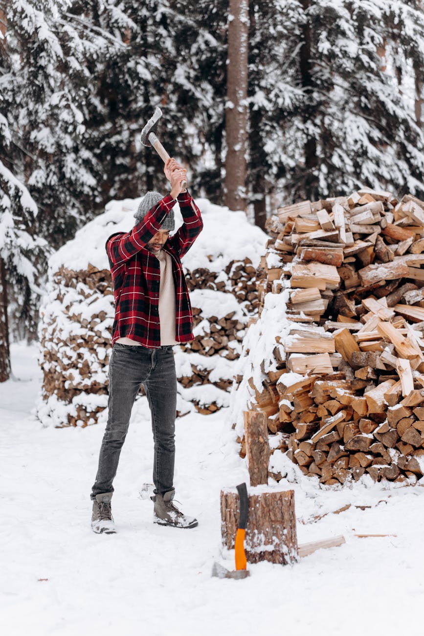 Man chopping wood in snowy forest, winter preparation.