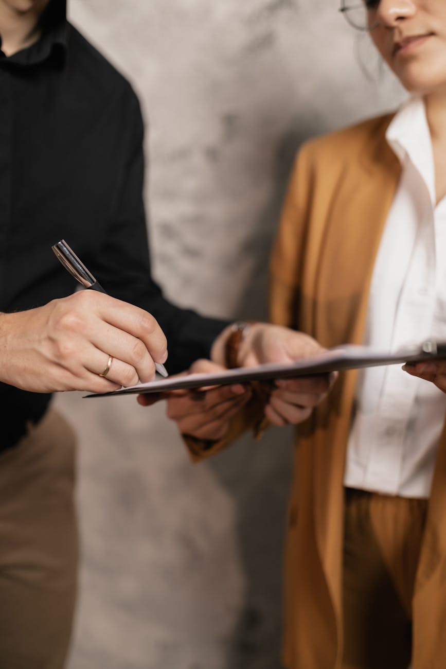 Close-up of two professionals signing a business document, emphasizing collaboration and negotiation.