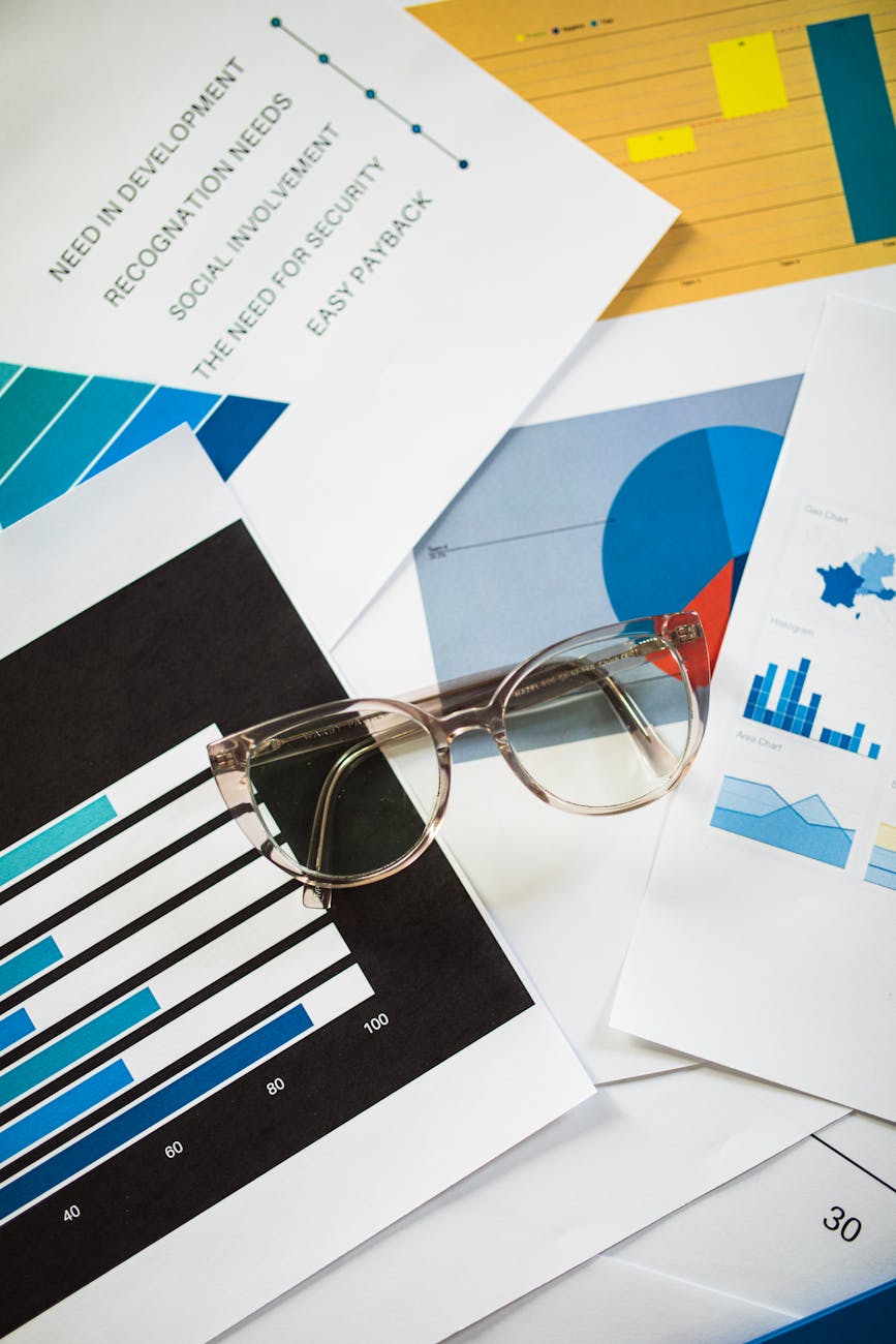 Eyeglasses resting on business charts and documents, ideal for financial analysis themes.